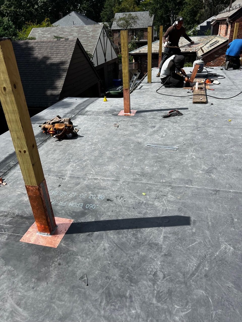 Flat EPDM roof installation with copper-clad post boots